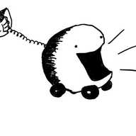 a large round robot with four little wheels and an enormous open mouth. a coiled wire leads from its back which ends in a receiver held by a human hand.