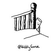 A cylindrical robot hanging from a bedpost, extending one arm down below the level of the quilt. Its tongue is sticking out in concentration.